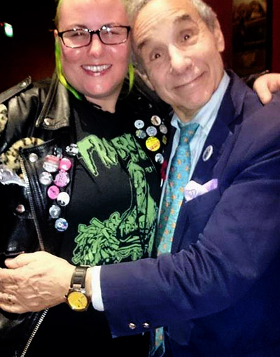 Lloyd Kaufman showing trasharama T-shirts the love